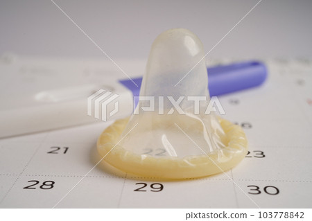 Pregnancy test and condom for female on calendar, ovulation day. 103778842