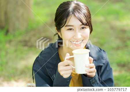 Photo of a woman drinking coffee outdoors 103779717