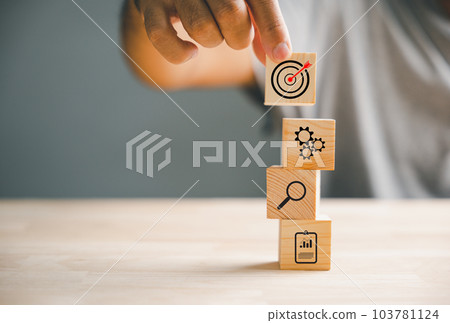 Businessman's hand arranging wood blocks with precision, depicting a business strategy and Action plan. This image represents the concept of business development and success. Businessman's hand arranging wood blocks with precision, depicting a business strategy and Action plan. This image represents the concept of business development and success. 103781124