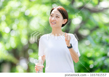 Woman jogging with water Early summer fresh green Woman jogging with water Early summer fresh green 103781557
