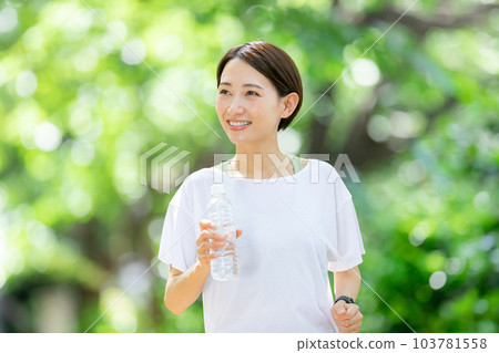 Woman jogging with water Early summer fresh green Woman jogging with water Early summer fresh green 103781558