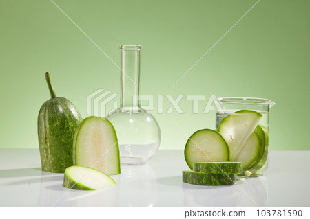 Fresh winter melon slices and some lab glassware decorated on a light green background. Blank space for cosmetic product of winter melon extract presentation. Front view 103781590