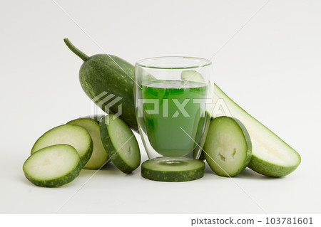 Against the white background, a glass of juice surround by winter melon slices. Scene for advertising drinking product with winter melon ingredient. Winter melon helps to lose weight extremely well. 103781601