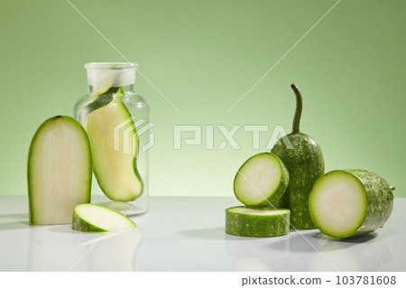 Creative background for advertising cosmetic with ingredient from winter melon. Some slices of winter melon and lab glassware decorated on a light green background. Space to place your product Creative background for advertising cosmetic with ingredient from winter melon. Some slices of winter melon and lab glassware decorated on a light green background. Space to place your product 103781608