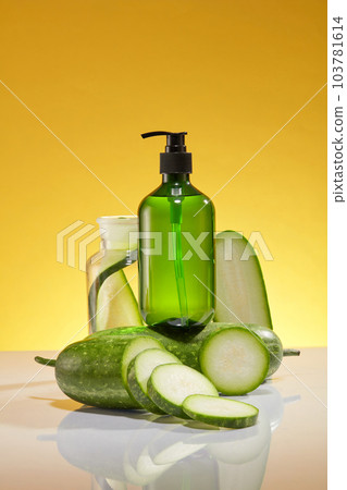 Mockup scene for advertising product with winter melon ingredient. A green pump bottle unlabeled placed on a fresh winter melon decorated on a yellow background. Space for design 103781614