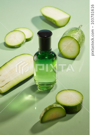 A glass bottle unbranded placed on green background with fresh winter melon slices. Winter melon contains a high amount of vegetable oil, which is very beneficial for skin and hair A glass bottle unbranded placed on green background with fresh winter melon slices. Winter melon contains a high amount of vegetable oil, which is very beneficial for skin and hair 103781616