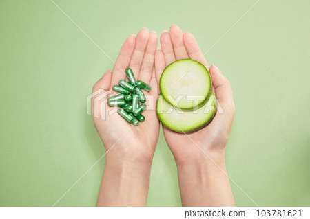 Young woman holds fresh slices of winter melon in one hand, vitamins capsules in the other. Winter melon is a natural ingredient rich in vitamins and minerals that good for health Young woman holds fresh slices of winter melon in one hand, vitamins capsules in the other. Winter melon is a natural ingredient rich in vitamins and minerals that good for health 103781621