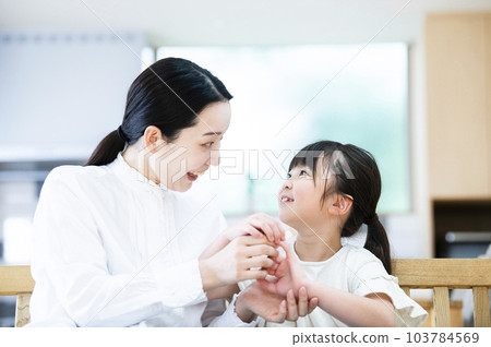 Mother putting a band-aid on her daughter 103784569