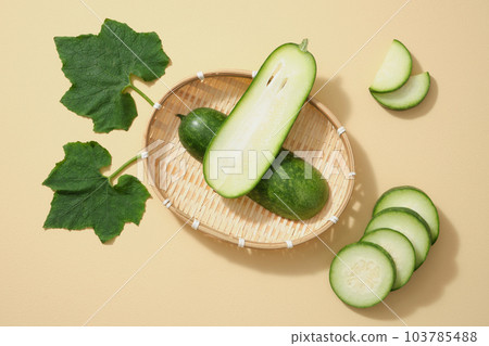Against a bamboo basket, fresh winter melon cut in half, some slices and leaf of winter melon decorated on a beige background. Winter melon is one of the popular foods in daily meals in Vietnam 103785488