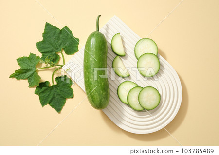 Top view of fresh winter melon slices and leaf displayed on beige arch podium on a beige background. Advertising scene for a product with winter melon  ingredients with many great health benefits 103785489