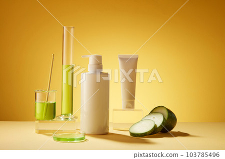 Laboratory concept for advertising cosmetic of winter melon extract. White bottles unbranded decorated with lab glassware containing green liquid and fresh winter melon slices on yellow background. Laboratory concept for advertising cosmetic of winter melon extract. White bottles unbranded decorated with lab glassware containing green liquid and fresh winter melon slices on yellow background. 103785496
