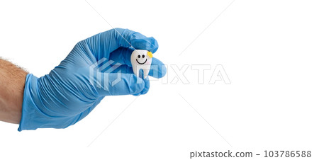 Hand in blue glove holding a tooth model with a smiley face Hand in blue glove holding a tooth model with a smiley face 103786588