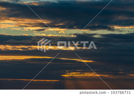 The sun's light gilds the dark storm clouds at dawn 103786731