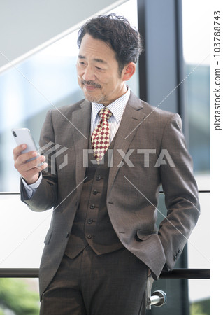 Image of a handsome manager or president looking at a smartphone 103788743
