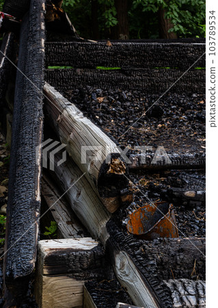 Destroyed by fire wooden house completely burned to the ground .ruins of a burnt wooden house after a fire Destroyed by fire wooden house completely burned to the ground .ruins of a burnt wooden house after a fire 103789534