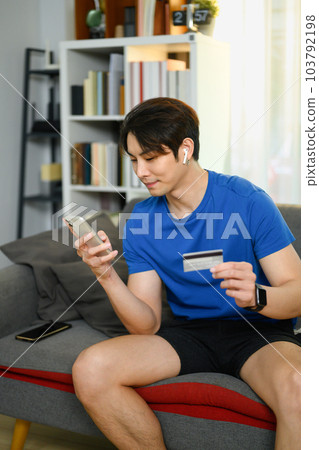 Portrait of asian man in casual clothes holding credit card, paying bill with online payment via internet on smart phone Portrait of asian man in casual clothes holding credit card, paying bill with online payment via internet on smart phone 103792198