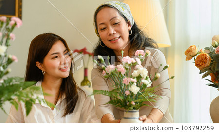 Happy Asian senior woman and adult daughter creating beautiful bouquet with different flowers at floral shop. Small business concept 103792259
