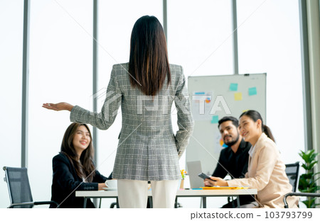 Back of business woman with long hair present about the project in front of her coworkers and happy 103793799