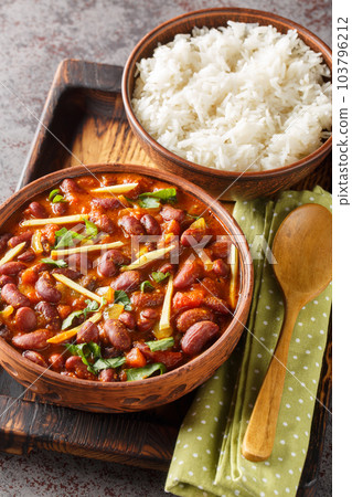 Rajma masala is a Indian vegetarian dish consisting of red kidney beans in a thick gravy with many spices served with rice close-up on a wooden tray. Vertical Rajma masala is a Indian vegetarian dish consisting of red kidney beans in a thick gravy with many spices served with rice close-up on a wooden tray. Vertical 103796212