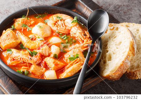 Seafood and fish stew such as shrimp, mussels, scallops, squid with tomatoes close-up in a bowl. Horizontal 103796232