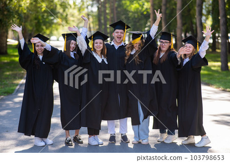 Group of happy graduates in robes outdoors.  Group of happy graduates in robes outdoors.  103798653