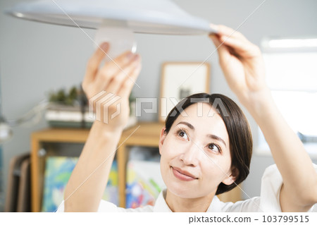 Young woman exchanging light bulbs Lifestyle image 103799515
