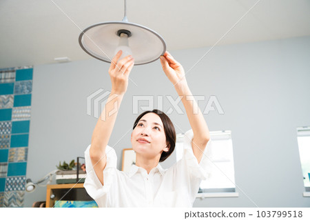 Young woman exchanging light bulbs Lifestyle image Young woman exchanging light bulbs Lifestyle image 103799518