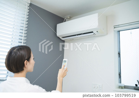 操作空調的年輕女性生活方式形象 操作空調的年輕女性生活方式形象 103799519