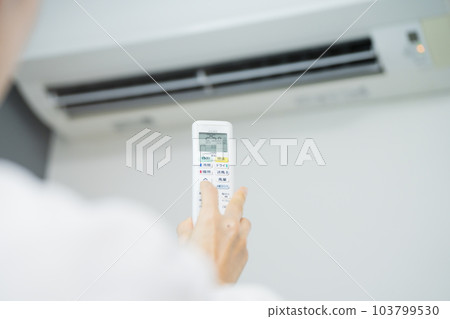 Young woman operating the air conditioner Lifestyle image 103799530