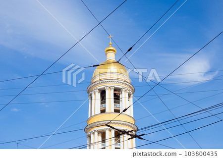 golden dome of bell tower of Cathedral of Vladimir Icon of Mother of God and wires on blue sky. view from below from street. St. Petersburg, Russia 103800435