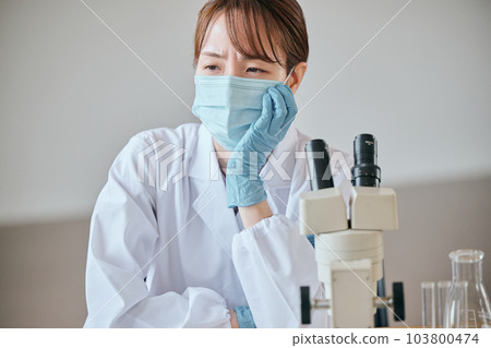 A young woman in a white coat with a melancholy expression at her desk A young woman in a white coat with a melancholy expression at her desk 103800474