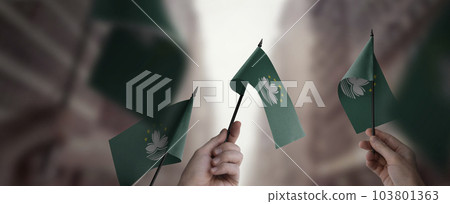 A group of people holding small flags of the Macao in their hands A group of people holding small flags of the Macao in their hands 103801363
