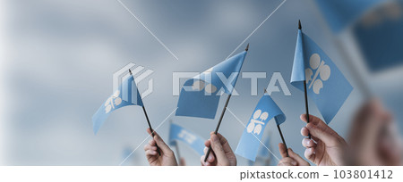 A group of people holding small flags of the Organization of the Petroleum Exporting Countries in their hands A group of people holding small flags of the Organization of the Petroleum Exporting Countries in their hands 103801412