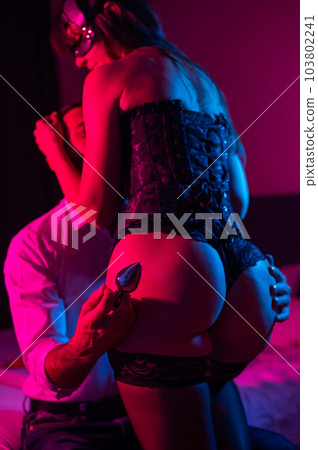 The man is holding an anal plug. Close-up of female buttocks in underwear. Sexual preferences of the couple. 103802241