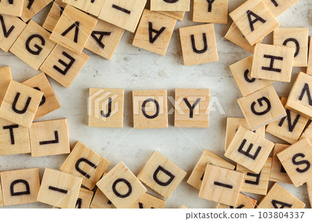 Top down view, pile of square wooden blocks with word JOY on white board. Top down view, pile of square wooden blocks with word JOY on white board. 103804337