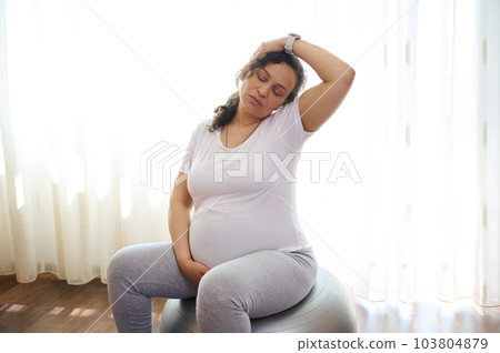 Gravid expectant woman, future mom expecting baby, practicing prenatal stretching exercising on fit ball. Sport. Fitness. Active healthy lifestyle in pregnancy time for easy childbirth and pain relief Gravid expectant woman, future mom expecting baby, practicing prenatal stretching exercising on fit ball. Sport. Fitness. Active healthy lifestyle in pregnancy time for easy childbirth and pain relief 103804879