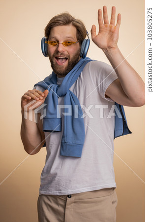 Young happy winner man listening music via headphones, dancing disco fooling around, celebrating Young happy winner man listening music via headphones, dancing disco fooling around, celebrating 103805275