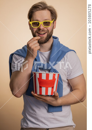 Excited caucasian man eating popcorn, watching interesting tv serial, sport game, film, online movie Excited caucasian man eating popcorn, watching interesting tv serial, sport game, film, online movie 103805278