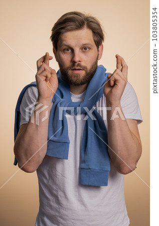 Young man crossed fingers looking at camera asking for good luck news dreaming about win victory 103805354