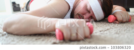 Tired man lies on floor with dumbbells Tired man lies on floor with dumbbells 103806320