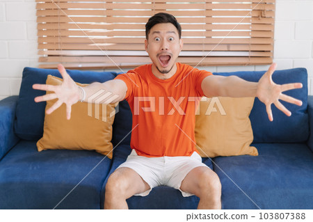 Wow and shocked face of man sit on the sofa in his home. 103807388
