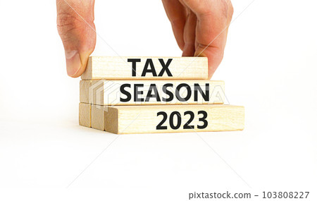 Tax season 2023 symbol. Concept words Tax season 2023 on wooden blocks on a beautiful white table white background. Businessman hand. Business Tax season 2023 concept. Copy space. 103808227