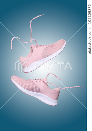 Pink women's sports sneakers with laces levitate on a blue background 103809876