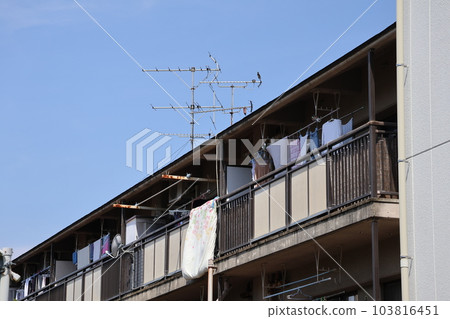 The scenery of the townscape with the blue sky and the collective housing where the futons are hung out on the veranda The scenery of the townscape with the blue sky and the collective housing where the futons are hung out on the veranda 103816451
