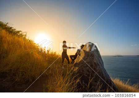 .Two women exercising on the top of a mountain..On the hilltop filled with the smell of the sea, .making it the perfect place to exercise relax and enjoy the scenery..golden sunrise shines background. .Two women exercising on the top of a mountain..On the hilltop filled with the smell of the sea, .making it the perfect place to exercise relax and enjoy the scenery..golden sunrise shines background. 103816854