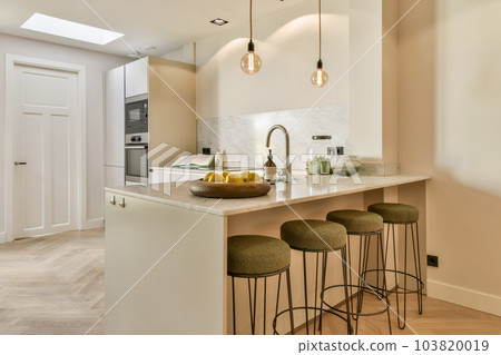 a kitchen with three stools and a bowl of fruit on the island in front of the counter is white 103820019