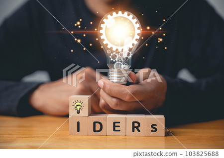 Question and solution concept. Person holding wooden block with light bulb icon, suggesting an answer with copy space. Innovation and problem-solving for corporate success. new ideas 103825688