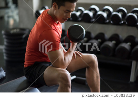 Asian strong man training biceps by heavy dumbbell in gym Asian strong man training biceps by heavy dumbbell in gym 103828129