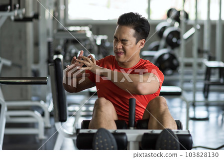 Asian fit man warm up stretching body before sit up in gym Asian fit man warm up stretching body before sit up in gym 103828130