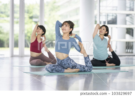 Young women doing yoga pigeon pose 103829697